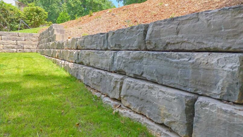 Completed boulder retaining wall with new grass started